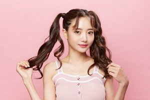 Asian woman with her hair in bunches on a pink background